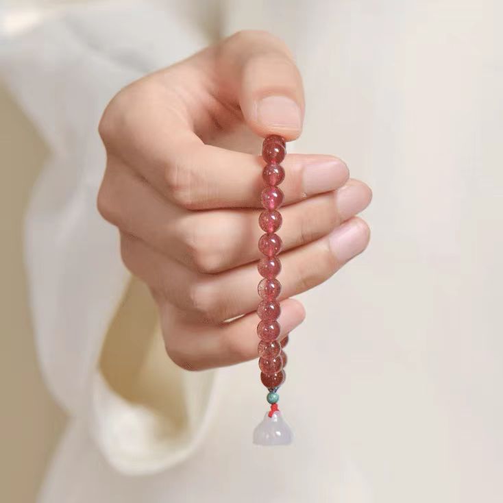 Hand holding a beaded bracelet with a plain background