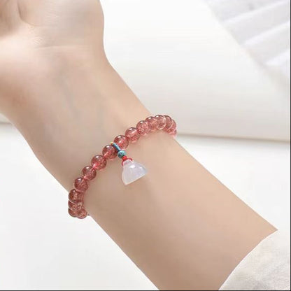 Pink beaded bracelet with a heart charm on a wrist against a white background