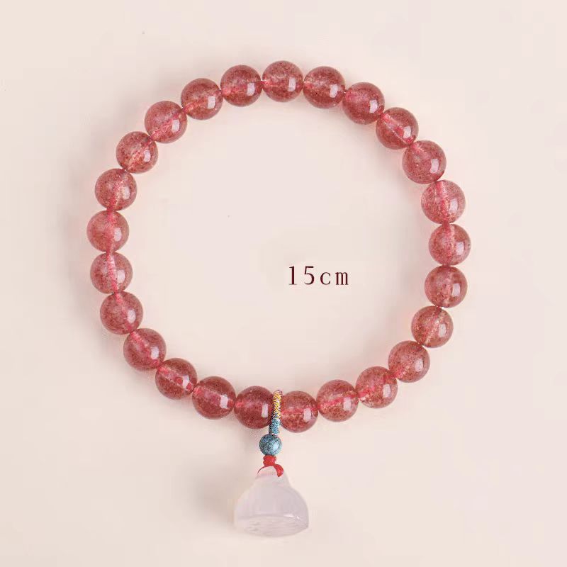 Pink beaded bracelet with a pendant on a light pink background