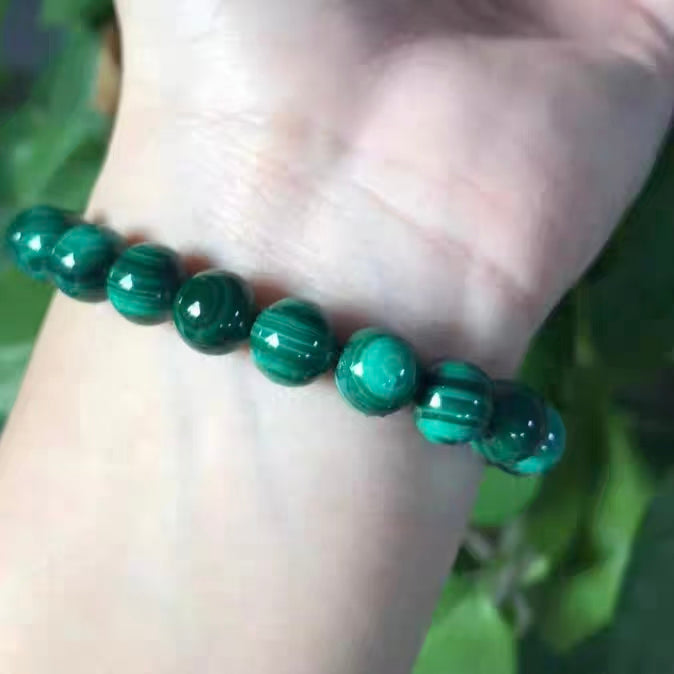 Green beaded bracelet on a wrist with a blurred green background