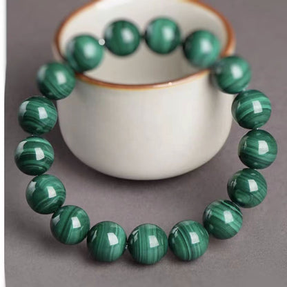 Green marbled bracelet on a gray surface with a white cup in the background