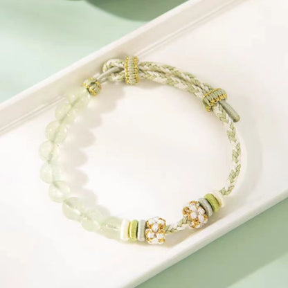 Bracelet with beads and gold accents on a white dish against a light green background