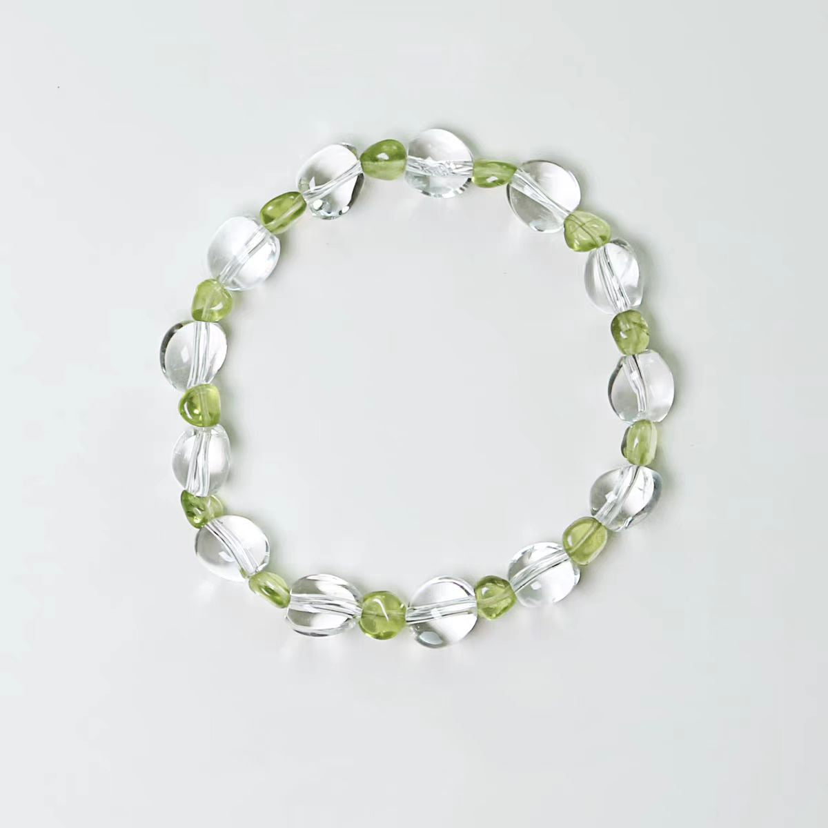 Bracelet with green and clear beads on a light gray background
