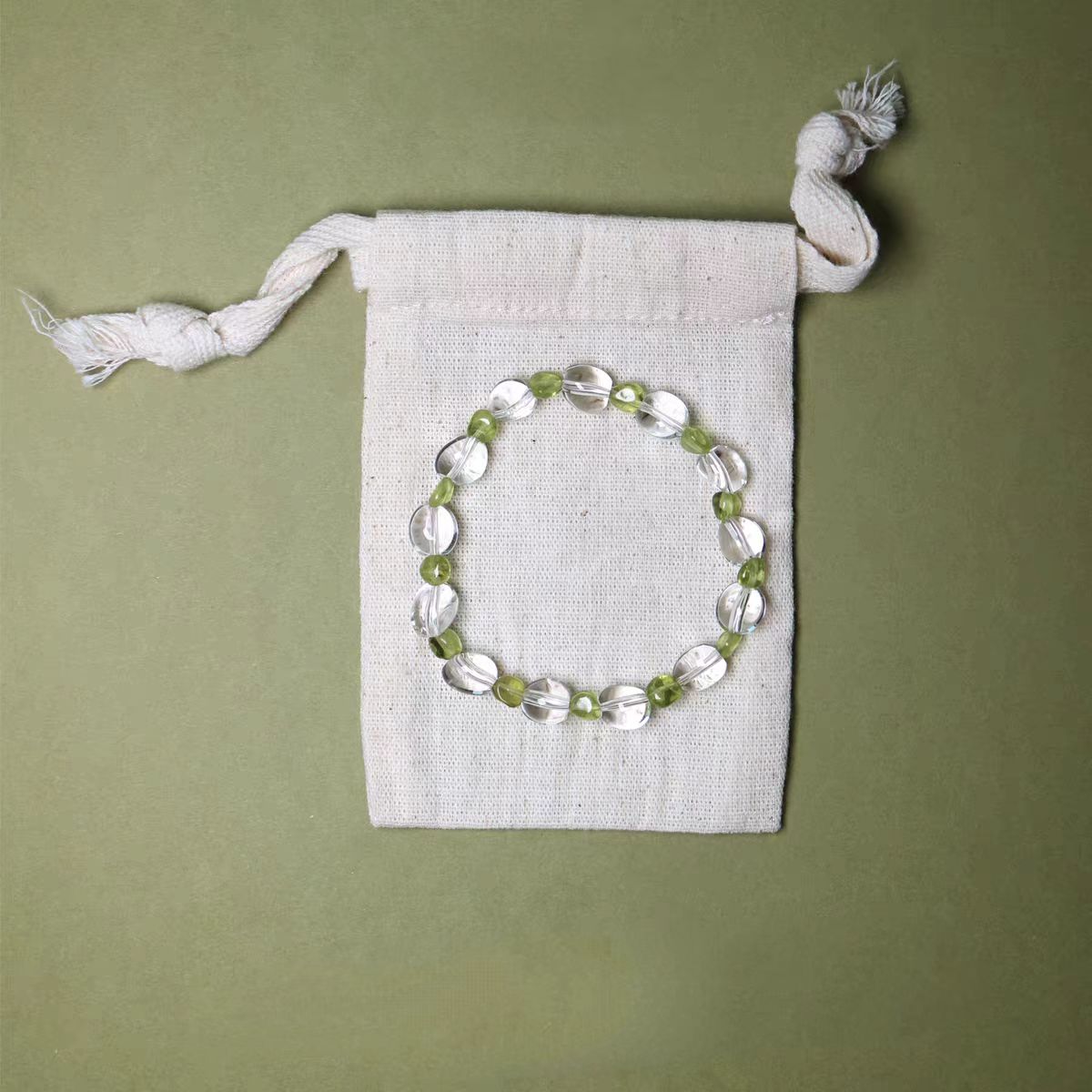 Beaded bracelet on a white drawstring bag against a green background