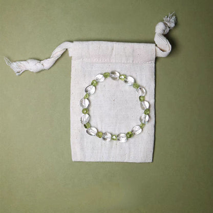 Beaded bracelet on a white drawstring bag against a green background