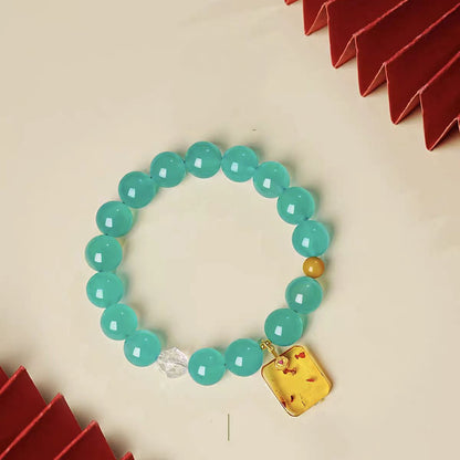 Turquoise beaded bracelet with a yellow tag charm on a beige background