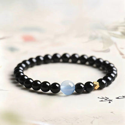 Black beaded bracelet with a blue cat's eye stone on a light background