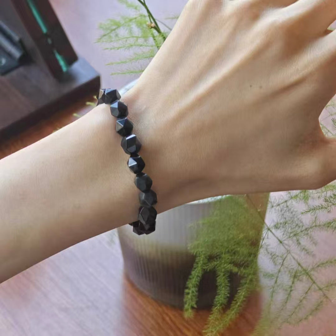 Black beaded bracelet on a wrist with a blurred indoor background