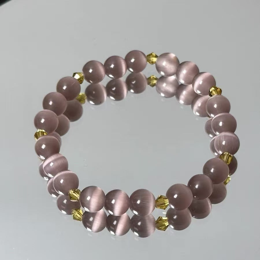 Pink beaded bracelet with gold accents on a light gray background