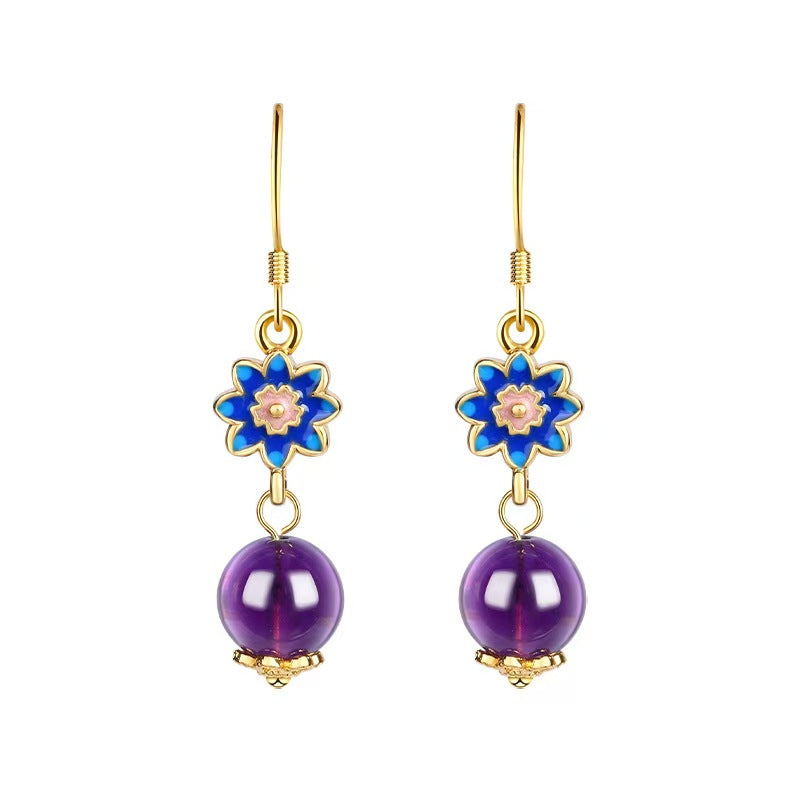 Pair of earrings with blue floral tops and purple beads on a white background