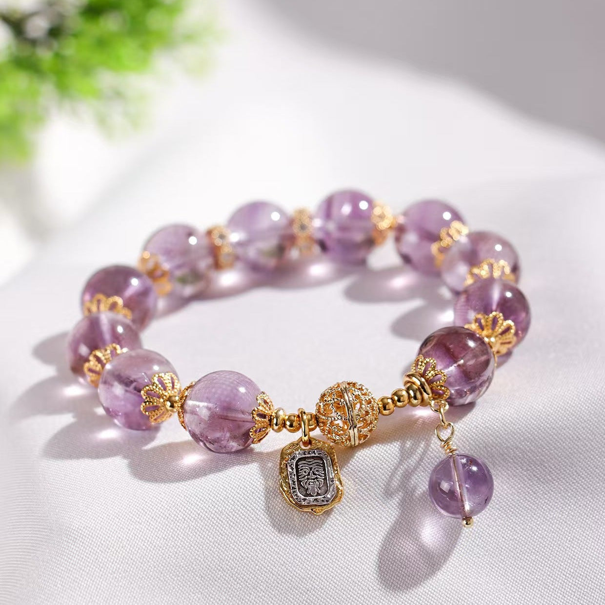 Purple beaded bracelet with gold accents on a white surface