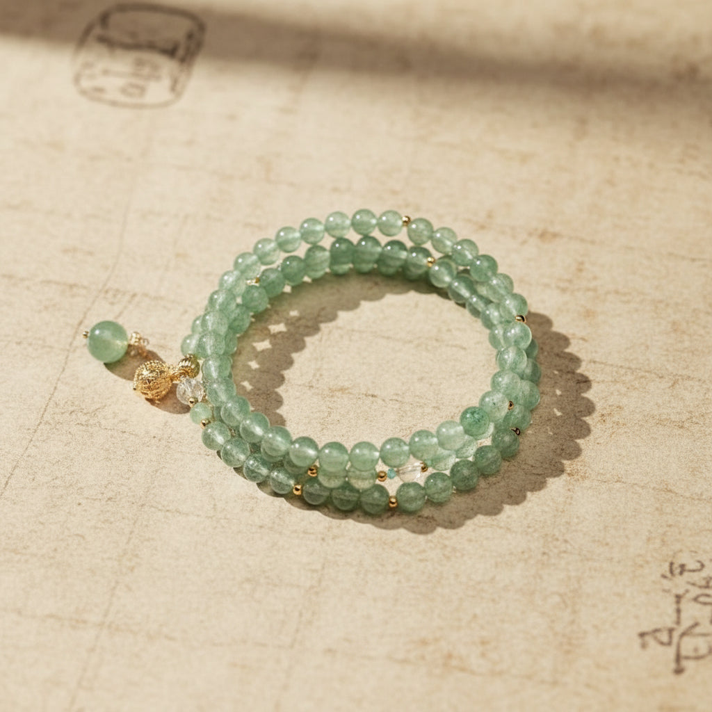 Green beaded bracelet with gold accents on a magazine page