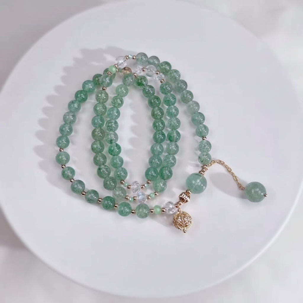 Green beaded necklace with a gold charm on a white plate, branded 