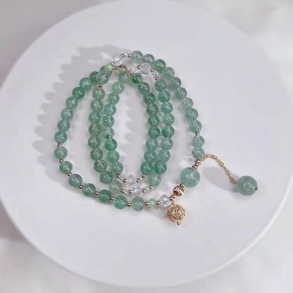 Green beaded necklace with a gold charm on a white plate, branded 