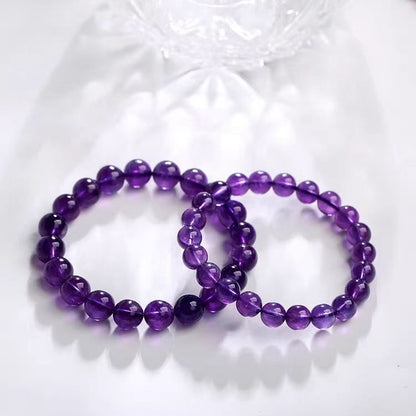 Two purple beaded bracelets on a textured white surface