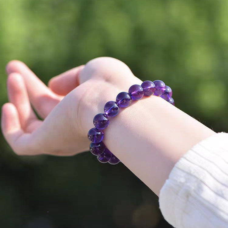 Purple beaded bracelet on a wrist with a blurred green background